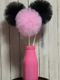 two pink vases with black and white pom - poms in them