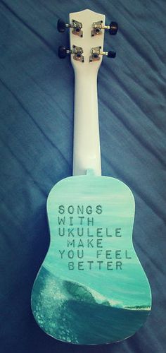 an ukulele with words written on it sitting on top of a black sheet