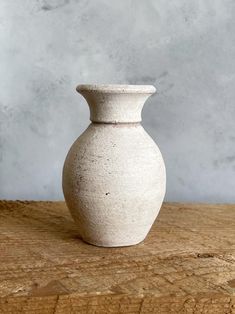 a white vase sitting on top of a wooden table