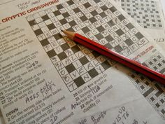 a red pencil sitting on top of a crossword puzzle