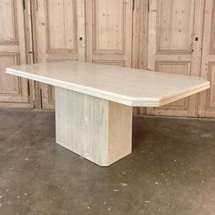 a white marble dining table in front of wooden paneled walls and flooring with doors behind it