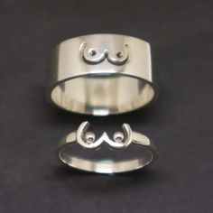 two silver rings sitting next to each other on top of a black surface with one ring in the middle