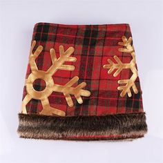 a red and black plaid blanket with gold snowflakes on the front, brown fur trim around the edges