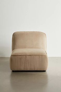 a beige couch sitting on top of a floor next to a white wall with a wooden frame