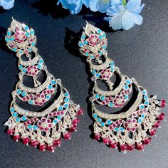 Featuring a pair of danglers in sterling silver embellished with rubies, turquoises and pearls. This combination is inspired from Turkish style of jewellery. This unique combination of stones adds an exotic flair to any look, while its timeless design ensures that these earrings can be treasured for years. Silver Jeweled Chandbali Chandelier Earrings, Turquoise Dangle Jewelry For Festivals, Turquoise Jewelry With Matching Earrings For Festivals, Fusion Style Turquoise Jewelry For Festivals, Turquoise Fusion Jewelry For Festivals, Fusion Turquoise Jewelry For Festivals, Silver Jeweled Bridal Earrings For Festivals, Elegant Turquoise Jewelry With Latkans, Turquoise Chandbali Jewelry With Latkans