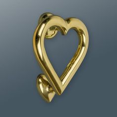 a gold heart shaped brooch sitting on top of a blue surface with two smaller hearts in the middle