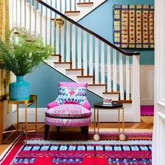 a brightly colored chair sits in front of a stair case and colorful rug on the floor