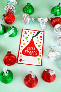 a christmas card surrounded by candy and candies on a green surface with foil wrapped around it