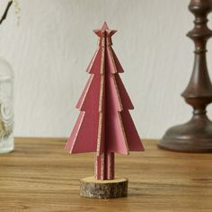 a small wooden christmas tree sitting on top of a table next to a glass bottle