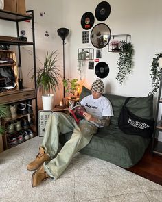 a man sitting on top of a green couch next to a wall filled with records