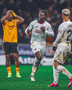 two soccer players are running on the field with one holding his hand up to his head