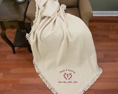 a white blanket sitting on top of a wooden floor next to a chair and table