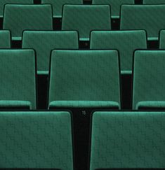 rows of green seats in an auditorium with numbers on the seat back and one at the front