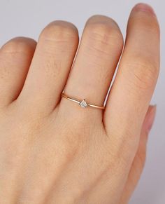 a woman's hand wearing a gold ring with a diamond on the middle finger