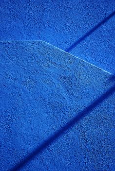 the shadow of a tennis racket on a blue wall