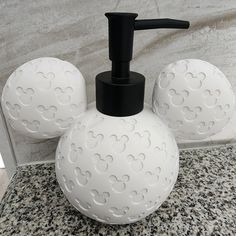 the soap dispenser is made out of white plastic balls with black handles