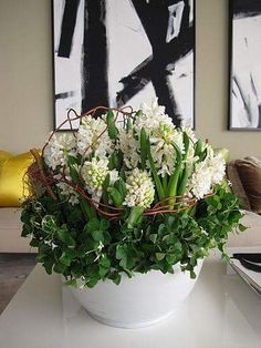 a white vase filled with flowers sitting on top of a table next to a painting