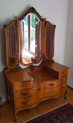 an antique dresser and mirror in front of a window