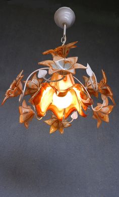 a chandelier hanging from a ceiling with flowers on the bottom and leaves around it