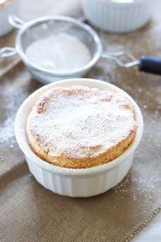 a cake in a white dish with powdered sugar on top and other baking utensils