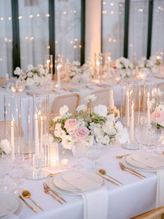 the table is set with white flowers and candles for an elegant wedding reception or special event