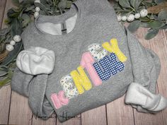 a gray sweatshirt with the word mom on it next to some flowers and leaves,