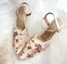 a pair of women's shoes with flowers on them sitting on a white surface