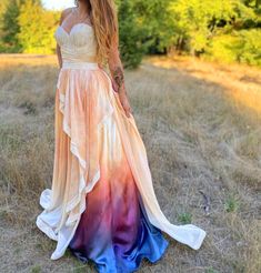 a woman in a long dress is standing in the grass