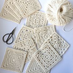 several crocheted squares are laid out on a table with scissors and yarn next to them