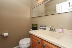 a white toilet sitting next to a sink in a bathroom under a mirror above it