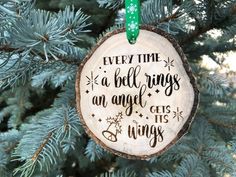 a wooden ornament hanging from a tree with the words, every time a bell rings an angel gets wings