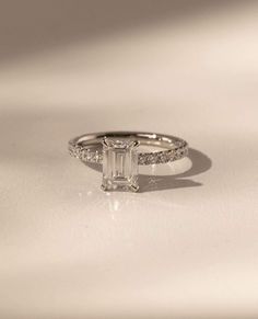 an emerald cut diamond ring with pave set shoulders