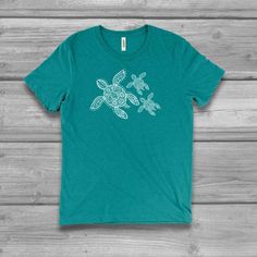 a green t - shirt with an image of two sea turtles on it