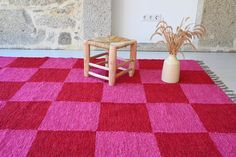 a red and pink rug with a wooden chair