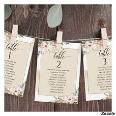 wedding seating cards hanging from clothes pins on a wooden background with eucalyptus leaves and greenery