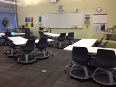 an empty classroom with desks and chairs in front of a whiteboard on the wall