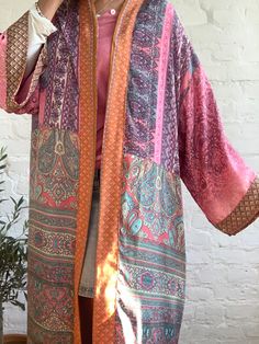 "This is one of a kind patchwork, upcycled silky robe Made free size with wrap tie closing and wide kimono sleeves Easy and fun to wear around the house or outside as a urban boho style, flowy kardigan with jeans and tshirt It is very comfy and feels soft and light the material is colourful indian saree silk made into this unique stylish over all MEAESURE free size length 55\" MATERIAL *saree silk, no lining CARE INSTRUCTIONS * Wash in warm water * Hand wash recommended * Hang to dry IMPORTANT N Pink Wrap Kimono In Bohemian Style, Pink Bohemian Wrap Kimono, Pink Bohemian Robe With Kimono Sleeves, Bohemian Pink Robe With Kimono Sleeves, Pink Long Sleeve Kimono With Patchwork, Long Pink Silk Robe, Pink Silk Wrap Kimono, Hippie Pink Kimono For Festival, Pink Hippie Kimono For Festival