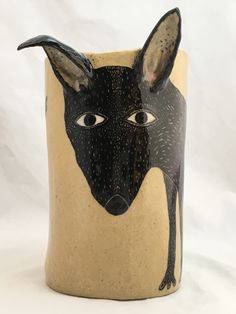 a black and tan vase with a dog's face painted on the outside of it