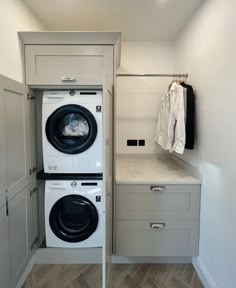 a washer and dryer in a small room next to each other with clothes hanging on the rack