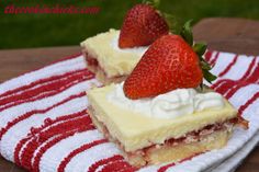 two pieces of cake with strawberries on top sitting on a red and white towel