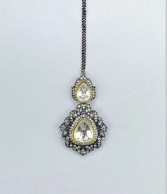 two tone gold and silver pendant with clear stones on chain, hanging from white background