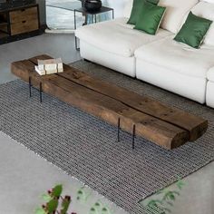 a living room with white couches and green pillows on the floor, along with a wooden coffee table