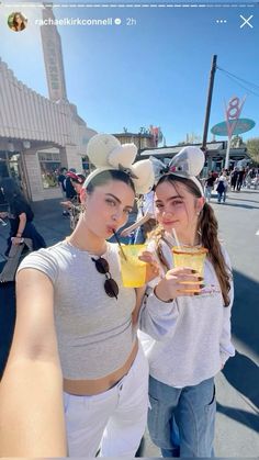 two young women standing next to each other holding drinks