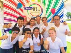 a group of people giving thumbs up in front of a colorful sign with the words sestaa 40th anniversary written on it