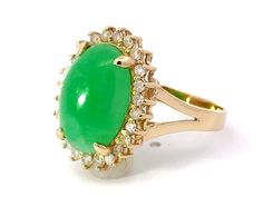 an oval shaped green stone surrounded by small white and yellow diamonds in a gold ring