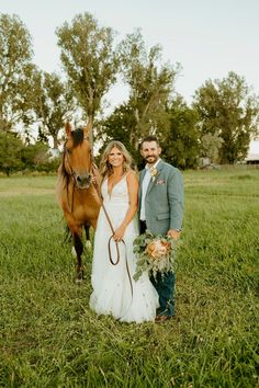 a bride and groom standing next to a horse