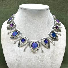 Here's a striking new necklace of handmade dichroic glass cabochons. They are set into fine silver bezels on domed, sterling, triangular drops. The domed drops are suspended on twisted and hammered wire links with silver granulation. A stunning accessory for special occasions. The video shows how some of the dichroic glass cabochons shift color as they move through different lighting, from blue and purple to pink and orange. It is light weight and comfortable to wear. The necklace is 19.75 inche Silver Glass Teardrop Jewelry, Silver Teardrop Necklaces With Unique Variations, Silver Cabochon Jewelry For Party, Silver Artisan Jewelry For Party, Artisan Silver Jewelry For Party, Silver Drop Glass Jewelry, Silver Teardrop Glass Necklaces, Silver Glass Cabochon Necklaces, Silver Necklace With Cabochon Glass