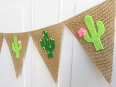 a burlap banner decorated with felt cactus and pink flowers