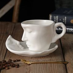 a white coffee cup sitting on top of a saucer next to some coffee beans