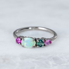 Our Splice Ring has been set with a solid Crystal opal from Lightning Ridge and shades of pink and teal sapphires. Opal measures 7 x 5mm. Band width 1.8mm. Gold weight in 14ct 3.1g approx. Pictured here with a high shine finish. For a matte finish please leave a note at checkout. Please note, we will match the opal as close to the image as possible, but each opal is unique and may vary in appearance and colour from what is depicted on the site. Multicolor Opal Multi-stone Rings, Crystal Opal, Lightning Ridge, Shades Of Pink, East West, Opal Crystal, Caicos Islands, Turks And Caicos Islands, Opal